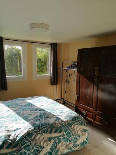 une chambre avec un lit et une commode et deux fenêtres dans l'établissement Maison avec jardin au calme proche de paris (30mn), à Longpont-sur-Orge