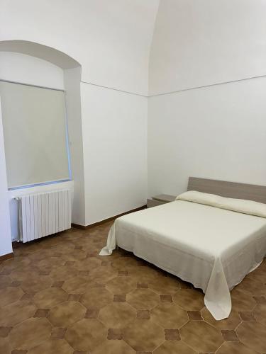a white bedroom with a bed and a window at La Casetta in Ordona