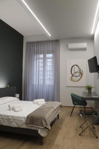 a bedroom with a bed and a desk and a window at IOLETTA HOUSE in Catania