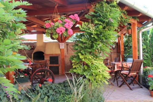 a patio with a table and chairs and flowers at Rozmann Family Panzió & Apartmanhaz in Sárvár