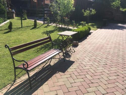 a park bench with a picnic table on a brick path at Rozmann Family Panzió & Apartmanhaz in Sárvár