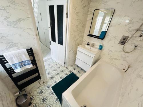 uma casa de banho com uma banheira, um lavatório e um espelho. em Elegant House in Stratford em Londres