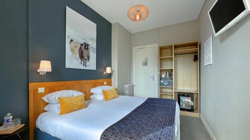 a bedroom with a bed and a tv on the wall at Hôtel Coeur De Loire in Nantes