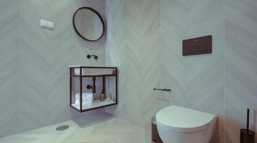 a white bathroom with a toilet and a mirror at Pedra de Sal - Hostel & Suites in Rio Maior