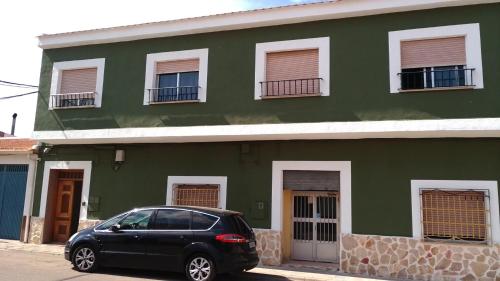 a black car parked in front of a green building at El Refugio Bed & Breakfast in Villarrobledo