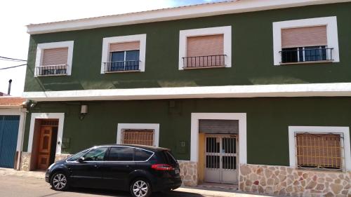 um carro preto estacionado em frente a um edifício verde em El Refugio Bed & Breakfast em Villarrobledo