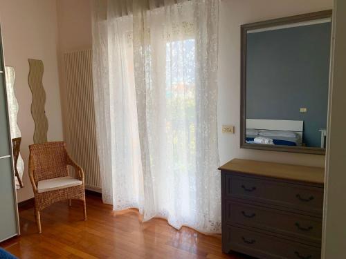 a bedroom with a dresser and a window with white curtains at BellAria Bliss Relax a 10 Minuti dal Cuore di Bologna con parcheggio privato in Bologna