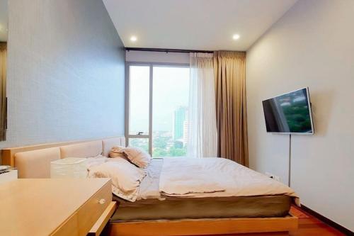 a bedroom with a bed and a large window at 5minsWalkThonglorBTS/1BR/wWorkingRM/Gym&Pool in Bangkok