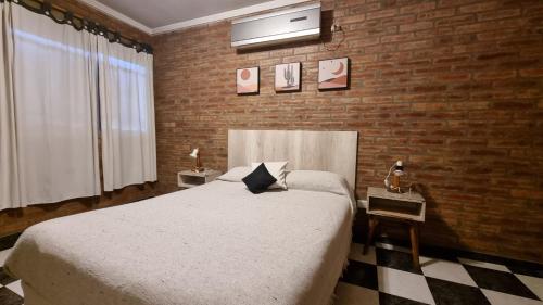 um quarto com uma cama e uma parede de tijolos em Pequeña Allegra em San Juan