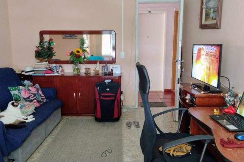 a living room with a couch and a desk with a computer at Quarto em apt compartilhado com estacionamento incluso in Niterói