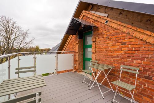 a balcony with two chairs and a brick building at Apteegimaja Apartment in Rõngu
