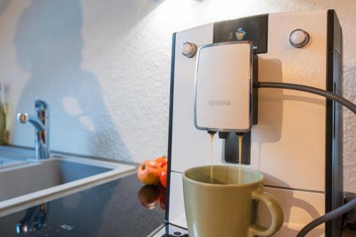 a cup of coffee is coming out of a coffee machine at Apteegimaja Apartment in Rõngu