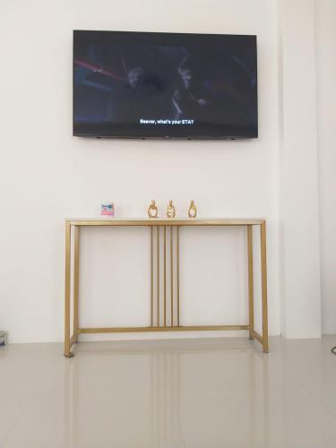 a television on a wall with a table underneath it at Little White House near Royal Farm Resort in Dipolog