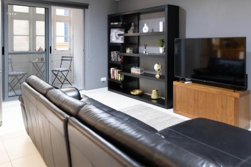 a leather couch in a living room with a television at Modern Central 2BR Flat in Valletta by Arco Collection in Valletta