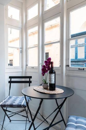 a table with a bottle of wine and flowers on it at Modern Central 2BR Flat in Valletta by Arco Collection in Valletta