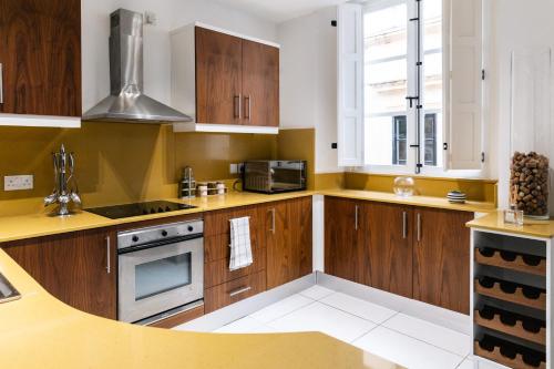 a kitchen with wooden cabinets and a stove top oven at Modern Central 2BR Flat in Valletta in Valletta