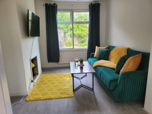 Affordable Home in Hatfield في هاتفيلد: غرفة معيشة مع أريكة خضراء وطاولة