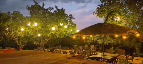 a patio with a table and chairs and an umbrella at Chalobahills Farmstay Resort in Ajra
