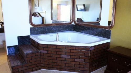 Royal Inn & Suites في تايلر: حمام مع حوض استحمام به مرآيتين