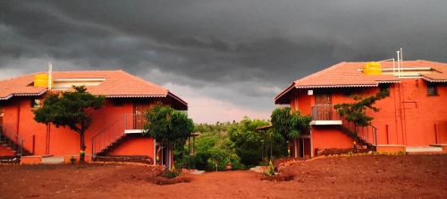two red houses on a hill with a cloudy sky at Chalobahills Farmstay Resort in Ajra