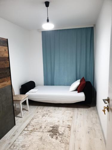 1 dormitorio con cama blanca y cortina azul en Budget Stay Guest House, en Kosovo Polje