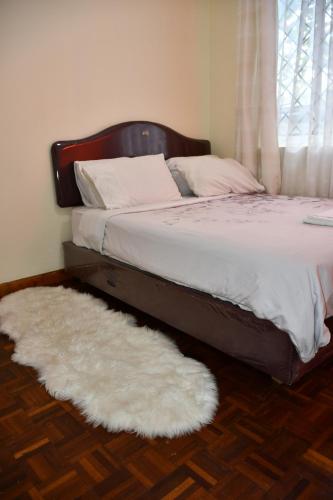 een bed met een wit tapijt naast een raam bij Stawi Apartment in Nairobi