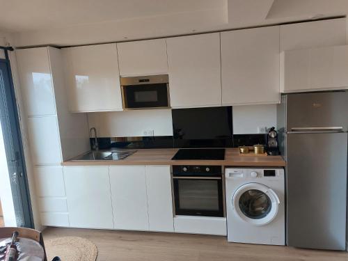 une cuisine avec des armoires blanches et une machine à laver dans l'établissement Appartement proche plage hendaye, à Hendaye