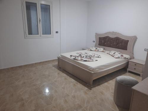 a white bedroom with a bed and a window at Villa du phare face à la mer in Taguermess