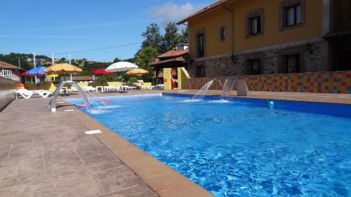 a swimming pool with a water slide in front of a building at Conjunto Hotelero La Pasera in Soto de Cangas