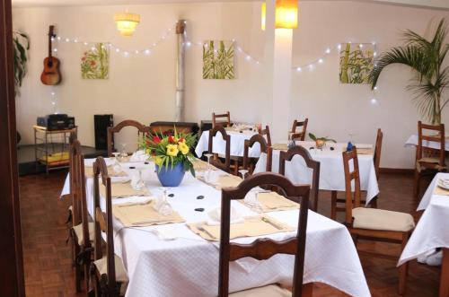 a dining room with white tables and chairs and a guitar at Hotel Mahavelo in Antananarivo