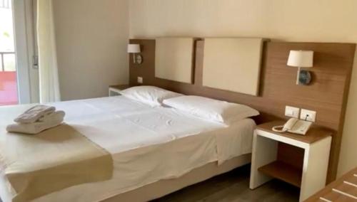 a bedroom with a white bed with a phone on a night stand at hotel villaggio Casarossa in Crotone