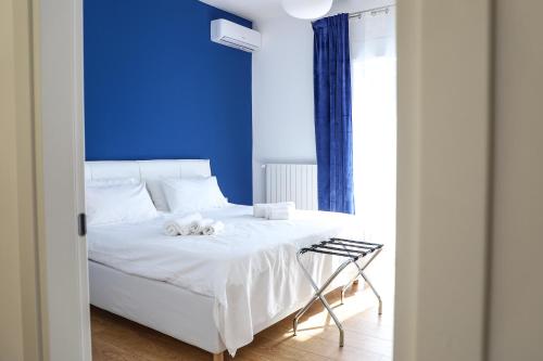 ein Schlafzimmer mit einem weißen Bett und einer blauen Wand in der Unterkunft Concept Apartment in Belpasso