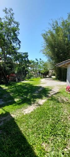 a field of grass with trees and a dirt road at Suíte o Pescador, praia do rosa in Garopaba