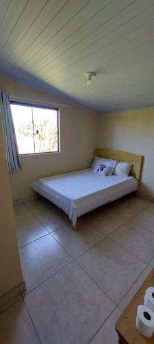 a bedroom with a bed in a room with a window at Suíte o Pescador, praia do rosa in Garopaba