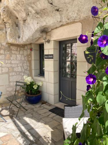a door of a house with purple flowers in front at Logis Hôtels Troglododo in Azay-le-Rideau