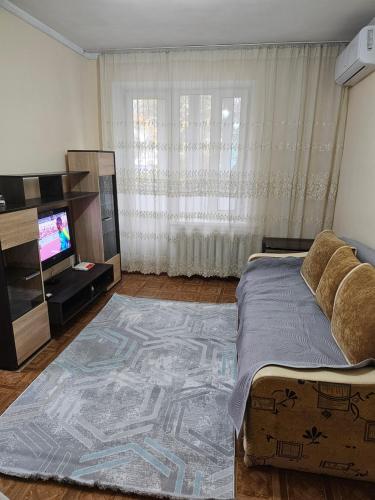 een woonkamer met een bed en een televisie bij Apartment Seifullina473 in Alma-Ata