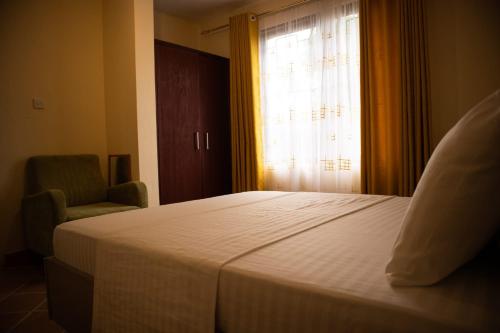 a bedroom with a bed and a chair and a window at Cosy Living near Bofa Beach in Kilifi