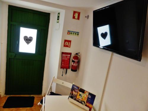 a green door with a window and a tv on a wall at Apartamento Embaixador Mateus in Lisbon
