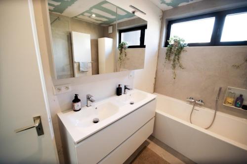 a bathroom with a sink and a tub and a mirror at Privé kamer met chill room en gedeelde badkamer - rand Antwerpen - afrit E313 Wommelgem - vlakbij tramhalte lijn 9 en 24 in Antwerp