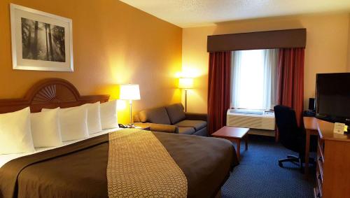 Sand SpringsにあるMagnuson Hotel Sand Springs – Tulsa Westの大きなベッドと椅子が備わるホテルルームです。