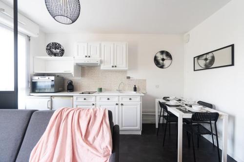 een keuken met witte kasten en een tafel met stoelen bij Le charmant Yin-Yang studio proche de Paris in Montrouge