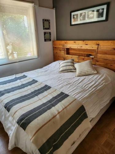 um quarto com uma cama grande e uma cabeceira em madeira em Casa 2 ambientes en Tesei, Hurlingham em Morón