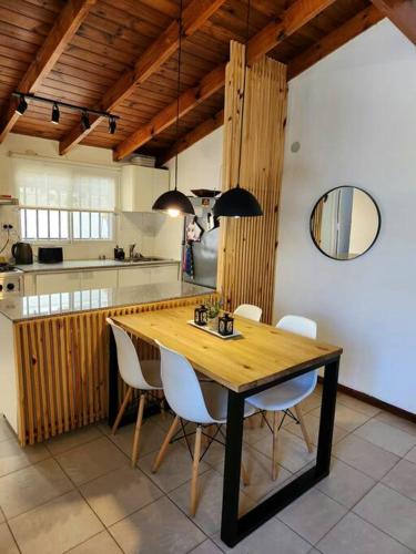 uma cozinha com uma mesa de madeira e cadeiras brancas em Casa 2 ambientes en Tesei, Hurlingham em Morón