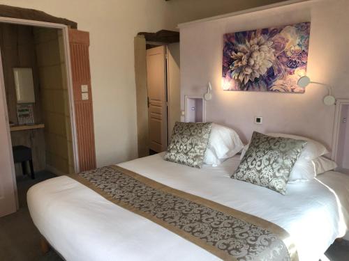 a bedroom with a white bed with a painting on the wall at Logis Hôtels Troglododo in Azay-le-Rideau