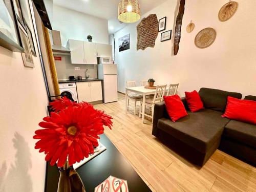ein Wohnzimmer mit einem schwarzen Sofa und einer roten Blume in der Unterkunft centro Madrid / chueca (1) in Madrid