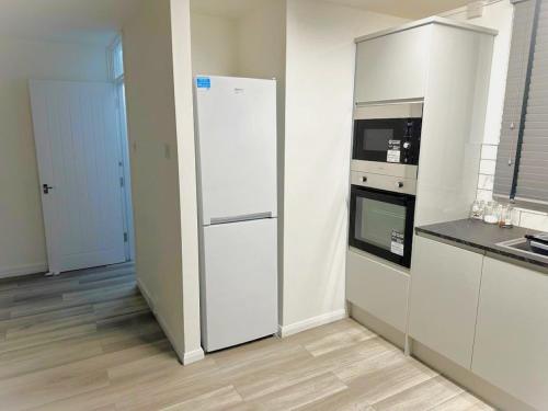 uma cozinha com um frigorífico branco e um fogão em Stylish Apartment At Carlton Grove em Londres