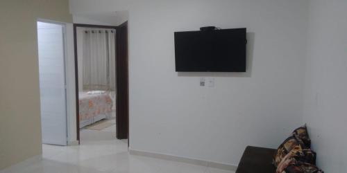 een woonkamer met een tv aan een witte muur bij Pousada La Belle in Maragogi