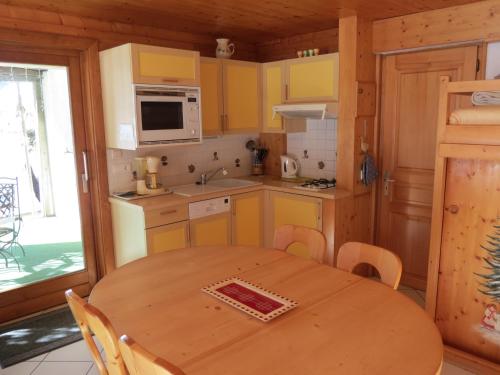 une cuisine avec une table en bois et des placards jaunes dans l'établissement Chalet Gypaète, à La Clusaz