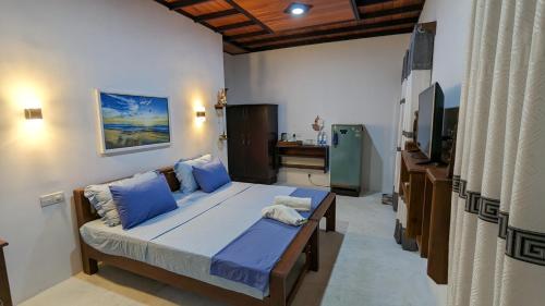 sypialnia z łóżkiem z niebieskimi poduszkami i telewizorem w obiekcie Jennifer's Villa w Negombo