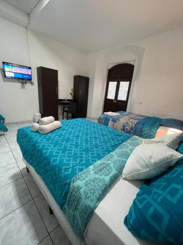 a bedroom with two beds with blue sheets and a television at Hotel y Café Ixmati Suchitoto in Suchitoto